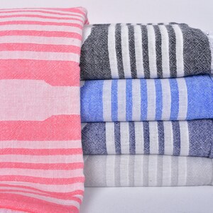 May include: A stack of five striped towels with fringed edges. The towels are in shades of pink, black, blue, grey, and white.