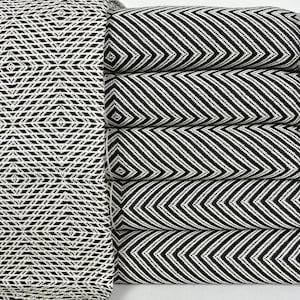 May include: A stack of five black and white patterned Turkish towels with fringe. The towels are folded and stacked on a white surface.