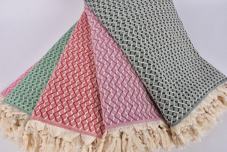 May include: Four woven cotton throws with fringe edges. The throws are in shades of green, red, purple, and black.
