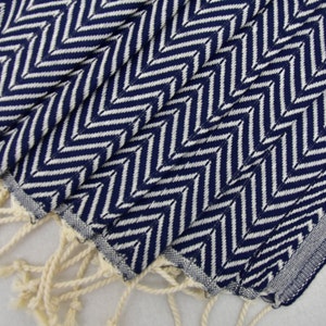 May include: A navy blue and white chevron patterned hand towel with white fringe.