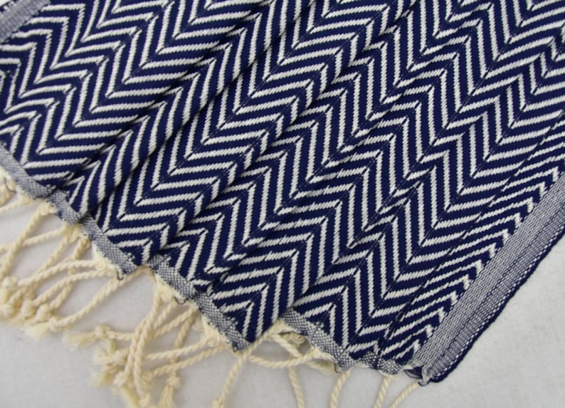 May include: A navy blue and white chevron patterned hand towel with white fringe.