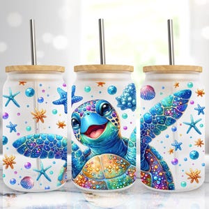 Puede incluir: Tres vasos de vidrio transparente con tapas de bambú y pajitas. Cada vaso presenta una tortuga de mar de dibujos animados colorida con un caparazón azul y un fondo blanco. El fondo está decorado con conchas marinas, estrellas de mar y burbujas de colores.