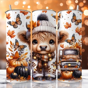 Puede incluir: Un vaso blanco con un diseño de temática otoñal. El diseño incluye una vaca de las Tierras Altas de dibujos animados con sombrero y bufanda, calabazas, mariposas y hojas de otoño. También aparece un camión marrón. El vaso tiene una pajita plateada.