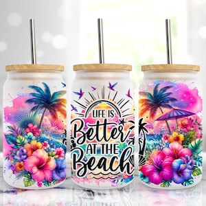 May include: Three white tumblers with bamboo lids and stainless steel straws. Each tumbler features a different design with a tropical beach theme. One tumbler has a palm tree and flowers, another has a sunset and the text "Life is Better at the Beach", and the third has a palm tree, umbrella, and flowers.