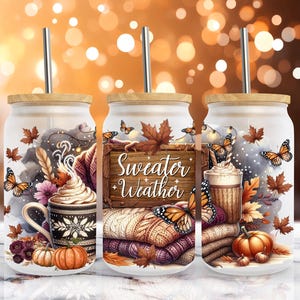 Könnte beinhalten: Drei Glasbecher mit Holzdeckeln und Metallstrohhalmen. Jeder Becher hat ein Herbst-Design mit Kürbissen, Schmetterlingen und dem Text "Sweater Weather". Die Designs umfassen eine Kaffeetasse, Blätter und gemütliche Pullover.
