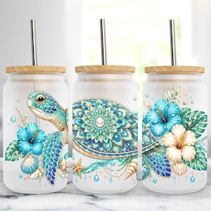 Op de afbeelding: Drie glazen bekers met matglas, bamboe deksels en metalen rietjes. Elke beker heeft een zeeschildpadontwerp met blauwe en turkooizen bloemenaccenten, schelpen en een zeester. Het ontwerp staat tegen een witte achtergrond.
