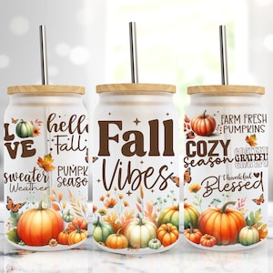 May include: Three white tumblers with brown lids and straws. Each tumbler features a different fall-themed design with pumpkins, butterflies, and fall-themed text. The text on the tumblers reads "Love sweater weather", "Hello Fall Pumpkin Season", and "Fall Vibes Cozy Season Farm Fresh Pumpkins Grateful Thankful Blessed".