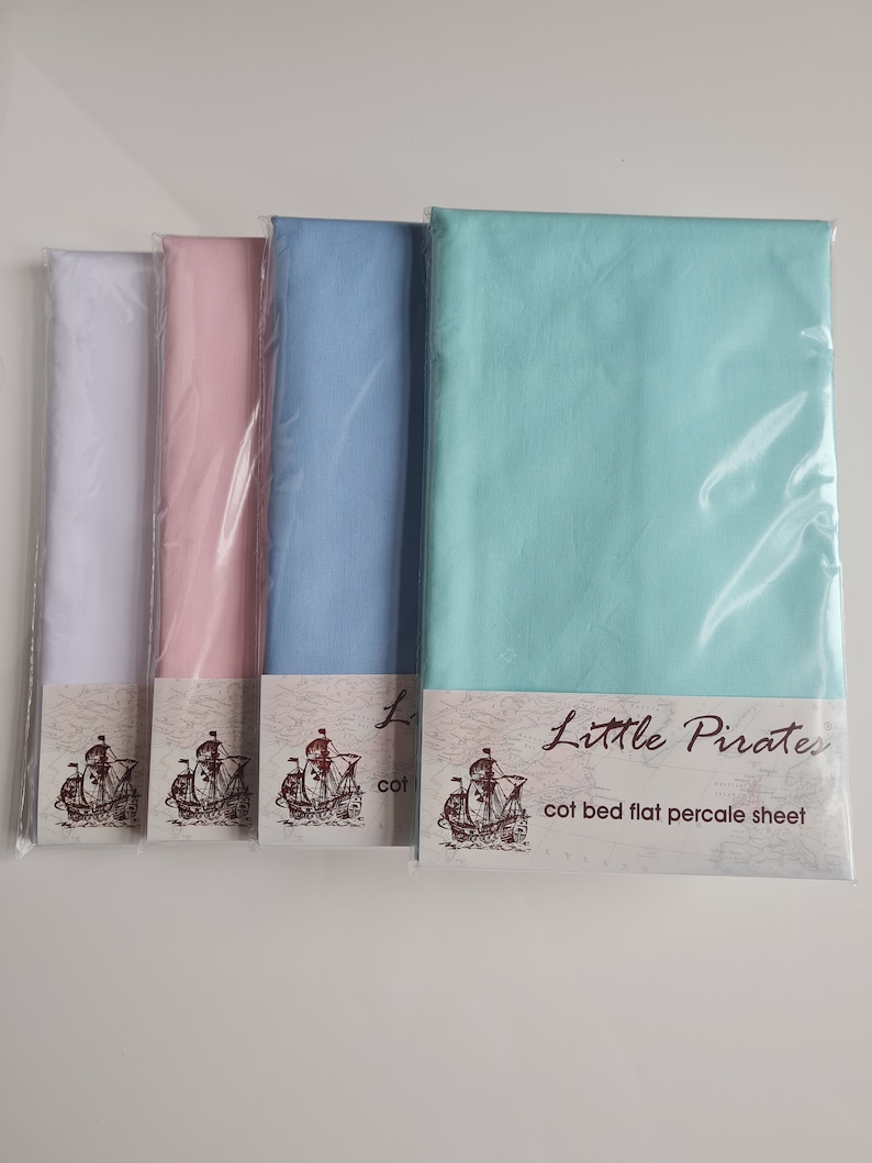 May include: Four cot bed flat percale sheets in white, pink, light blue, and teal, each in a clear plastic package. The sheets have the "Little Pirates" logo with a ship illustration. The text "cot bed flat percale sheet" is also visible.