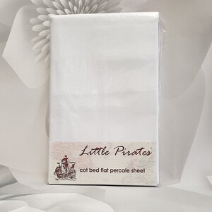 May include: A white cot bed flat percale sheet, packaged in clear plastic. The label features the text "Little Pirates" above an illustration of a sailing ship. The sheet is designed for a cot bed.