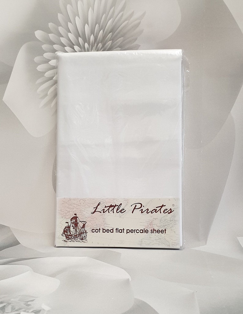 May include: A white cot bed flat percale sheet, packaged in clear plastic. The label features the text "Little Pirates" above an illustration of a sailing ship. The sheet is designed for a cot bed.