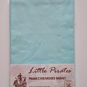 May include: A package of two flat percale sheets in a light blue color, designed for a pram, crib, or Moses basket. The packaging features the "Little Pirates" logo, a map design, and a graphic of a pram.