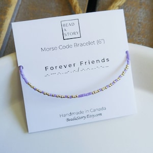 May include: A purple and silver beaded bracelet with the text "Forever Friends" in Morse code. The bracelet is displayed on a white card with the text "Bead a Story Morse Code Bracelet (6') Handmade in Canada BeadaStory.Etsy.com"