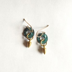 May include: A pair of earrings with a teal green metal ring and a gold metal teardrop charm.
