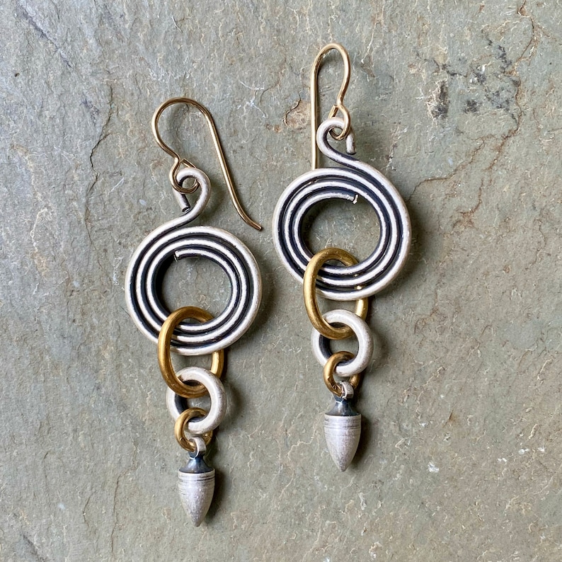 Pode incluir: Um par de brincos de prata e ouro com um design em espiral e uma forma de l&aacute;grima pendente.