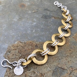 May include: A gold and silver bracelet with a hook clasp. The bracelet is made of interlocking circles.