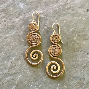 May include: A pair of gold-toned earrings with a spiral design. Each earring has three spirals connected by a curved wire.