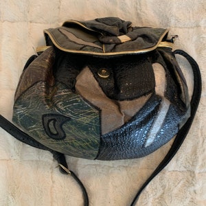 May include: A black leather patchwork crossbody bag with a gold trim and a flap closure. The bag has a long adjustable strap.