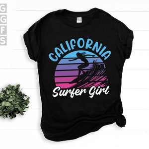 May include: Black t-shirt with a retro-style graphic of a surfer girl in front of a sunset with the text "California Surfer Girl".