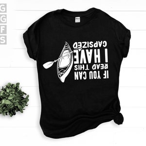 May include: Black t-shirt with a white graphic of a kayak and paddle. The text reads "IF YOU CAN READ THIS I HAVE CAPSIZED". The shirt is a crew neck style.