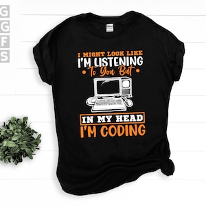 Pode incluir: Camiseta preta com o texto "I might look like I'm listening to you but in my head I'm coding" em branco e laranja. Um gráfico de um computador vintage está abaixo do texto. A camiseta tem gola redonda.