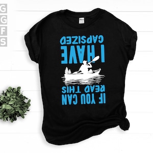 May include: Black t-shirt with blue text that reads "IF YOU CAN READ THIS I HAVE GAPSIZED". The design includes a white illustration of a person kayaking on water with trees in the background. The shirt also has SVG, PNG, DXF, and EPS file type logos.