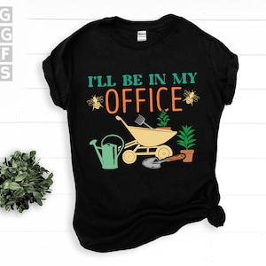 May include: Black t-shirt with the text "I'll be in my office" in white and yellow letters. The graphic features a wheelbarrow with plants, a shovel, and bees.