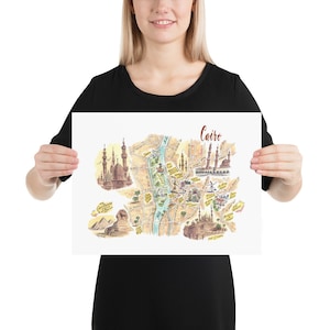 May include: A colorful illustrated map of Cairo, Egypt, with landmarks like the Great Sphinx, the Citadel, and the Mosque of Ibn Tulun. The map is printed on white paper and has a brown title bar with the word "Cairo" in cursive.