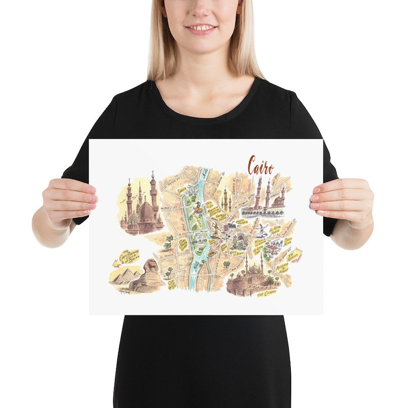 May include: A colorful illustrated map of Cairo, Egypt, with landmarks like the Great Sphinx, the Citadel, and the Mosque of Ibn Tulun. The map is printed on white paper and has a brown title bar with the word "Cairo" in cursive.