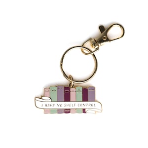 May include: Gold metal keychain with a stack of colorful books and a banner that reads "I have no shelf control".