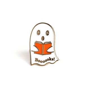 May include: A white ghost with big eyes and an open mouth is reading an orange book. The ghost is wearing a gold outline and the text "Booooks!" is written below the ghost.