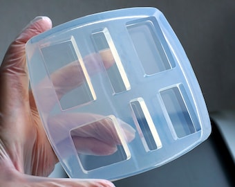 Puede incluir: Un molde de silicona transparente con seis cavidades rectangulares. El molde está diseñado para hacer objetos pequeños y rectangulares, como barras de jabón o manualidades de resina.