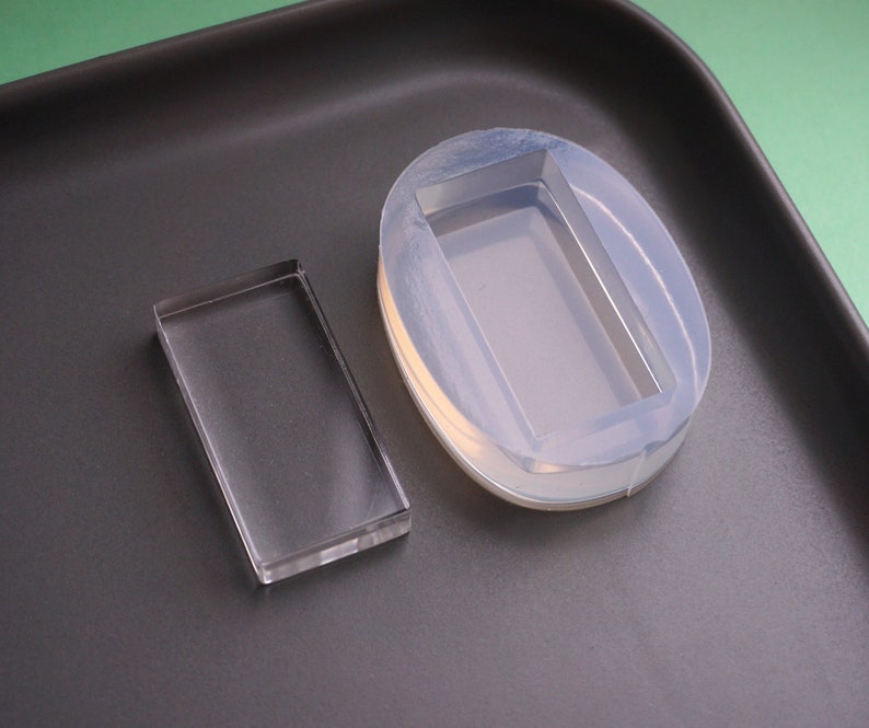 Peut inclure: Deux moules en silicone transparents pour la coul&eacute;e de r&eacute;sine. Un moule est rectangulaire et l'autre est ovale avec un encastrement rectangulaire.
