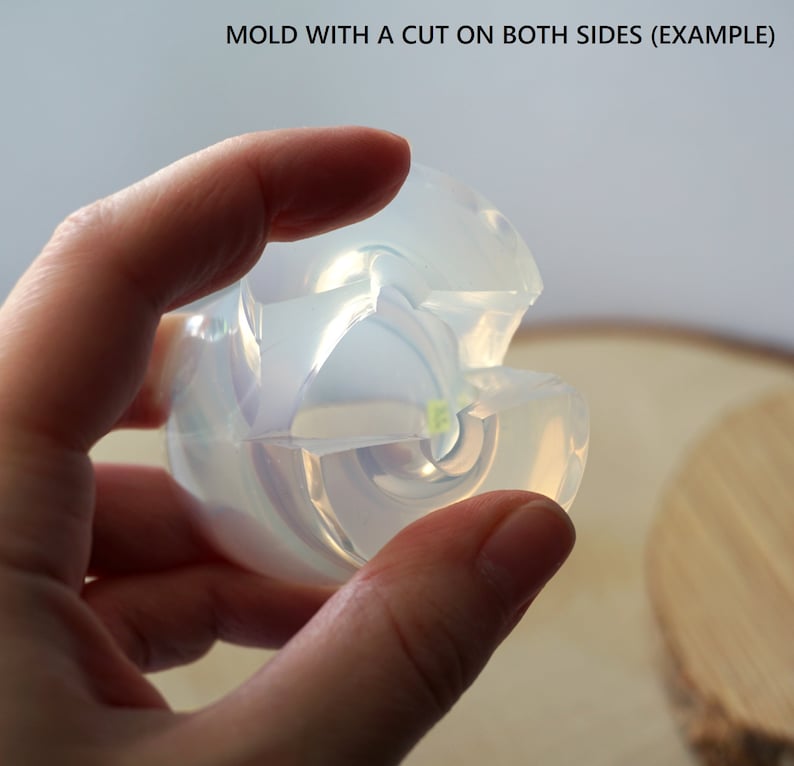 May include: A clear silicone mold with a cut on both sides. The mold is designed to create a round object with a swirl pattern.