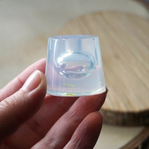 May include: Clear silicone mold for making a round, orb-shaped resin piece. The mold is held in a hand.