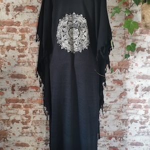 K&ouml;nnte beinhalten: Schwarzer Baumwoll-Kimono mit einem wei&szlig;en Mandala-Muster auf der R&uuml;ckseite. Der Kimono hat einen Fransenbesatz an Saum und &Auml;rmeln.