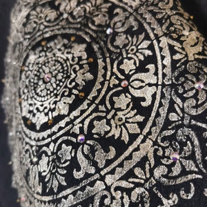 K&ouml;nnte beinhalten: Ein schwarzer Stoff mit einem silbernen Mandala-Design. Das Mandala ist mit Strasssteinen verziert.