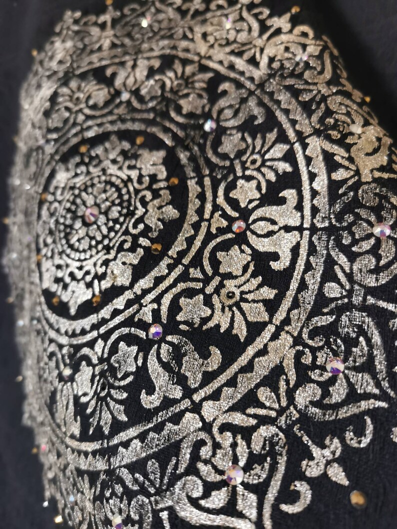 K&ouml;nnte beinhalten: Ein schwarzer Stoff mit einem silbernen Mandala-Design. Das Mandala ist mit Strasssteinen verziert.