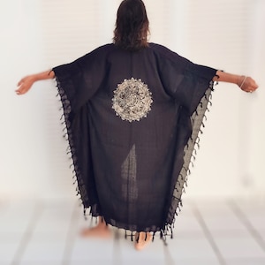 K&ouml;nnte beinhalten: Schwarzer Kimono mit einem goldenen Mandala-Muster auf der R&uuml;ckseite. Der Kimono hat Fransen an den R&auml;ndern.