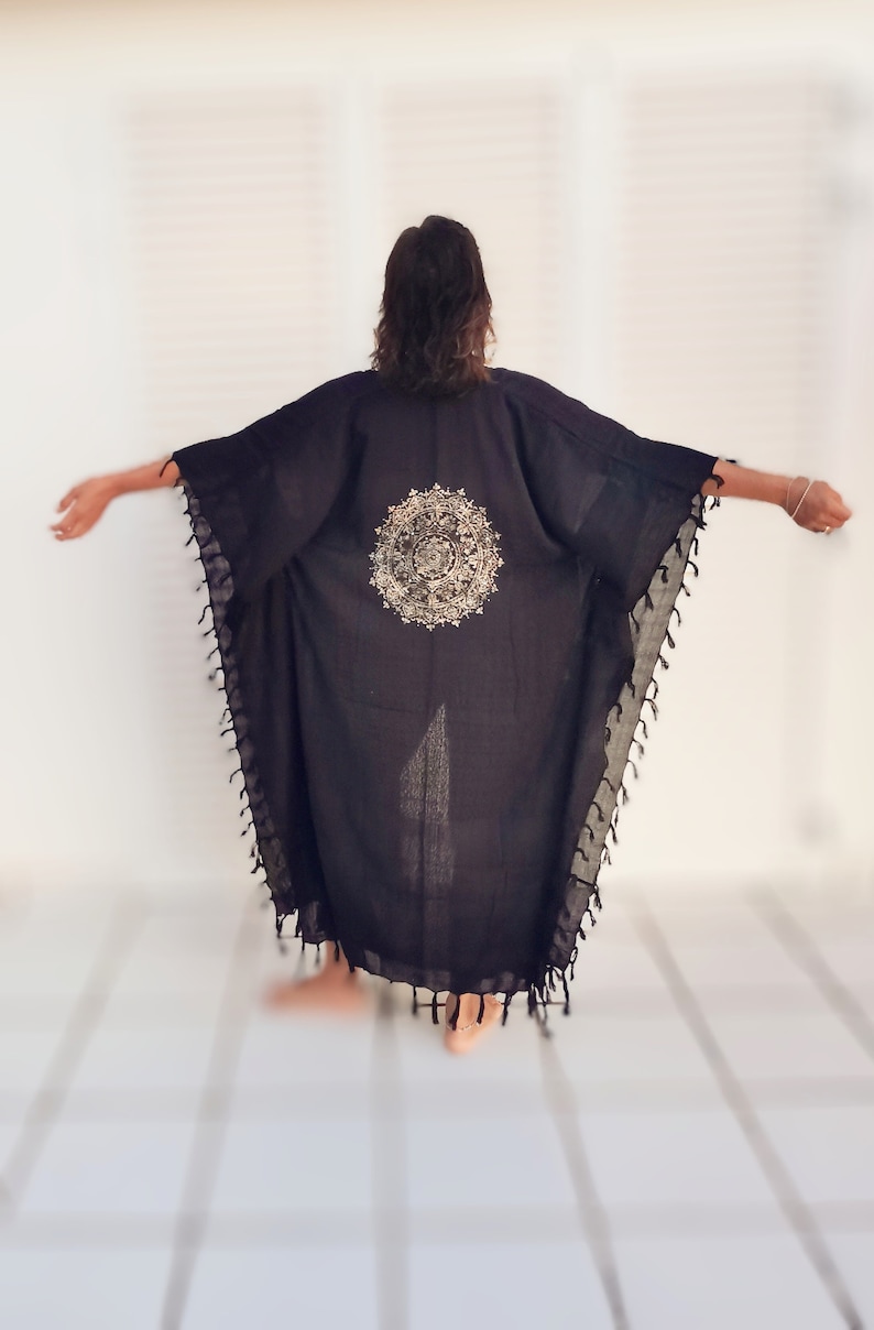K&ouml;nnte beinhalten: Schwarzer Kimono mit einem goldenen Mandala-Muster auf der R&uuml;ckseite. Der Kimono hat Fransen an den R&auml;ndern.