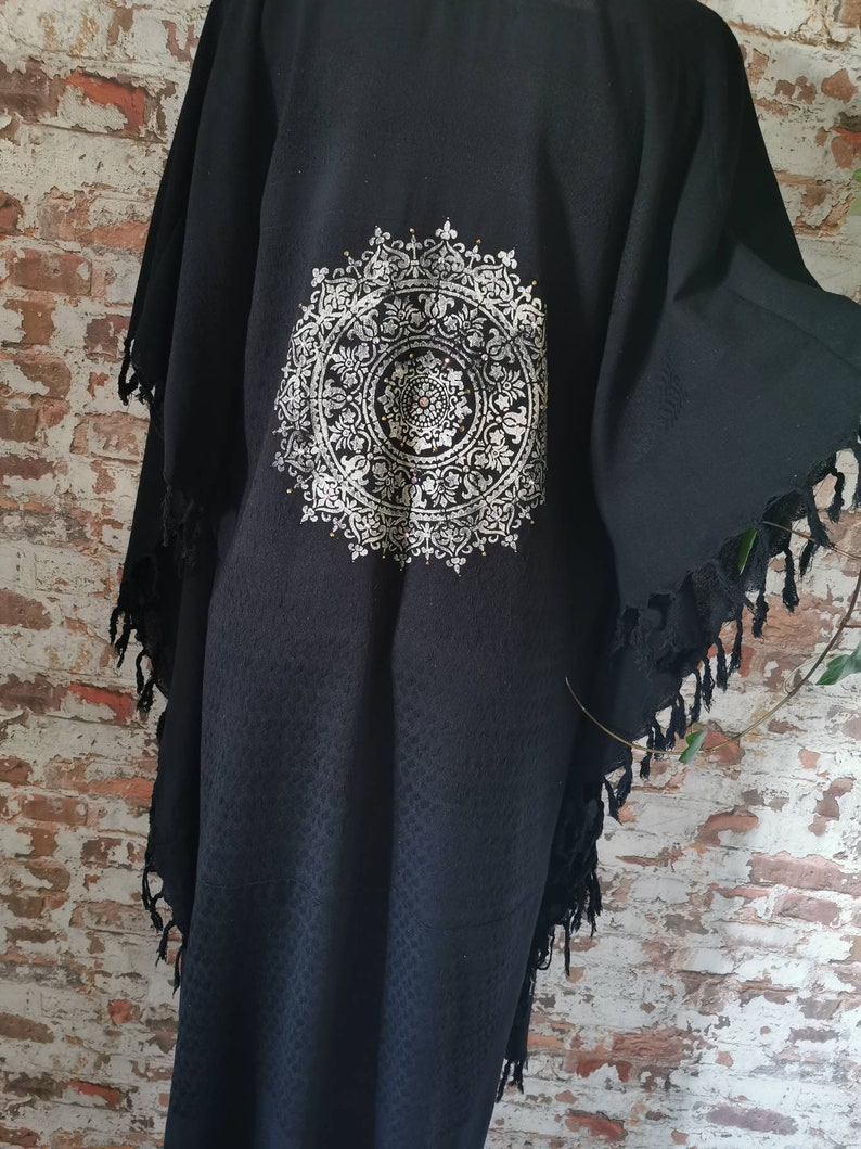 K&ouml;nnte beinhalten: Schwarzer Kimono mit einem silbernen Mandala-Design auf der R&uuml;ckseite. Der Kimono hat einen Fransenbesatz an Saum und &Auml;rmeln.