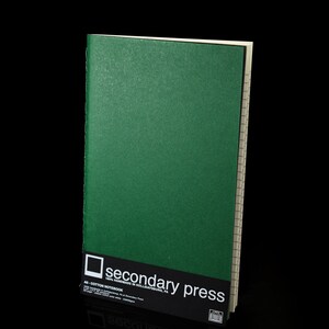May include: A green cotton notebook with the text "secondary press" printed on the front cover.