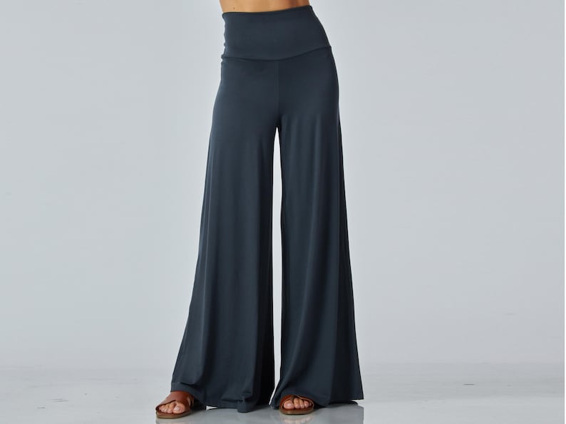 Puede incluir: Pantalones anchos de color gris carb&oacute;n oscuro s&oacute;lido con cintura de tiro alto. La prenda tiene un acabado liso y mate, con una silueta holgada y fluida que se extiende desde las caderas hasta el suelo, creando un ajuste relajado y c&oacute;modo.