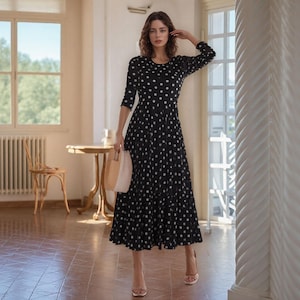 Puede incluir: Una taza de cerámica blanca con un asa negra y el texto "But First, Coffee" en negrita negra. La taza se encuentra sobre un fondo borroso, sugiriendo un ambiente acogedor.