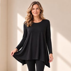 May include: A solid black long-sleeve tunic top featuring a round neckline and a flared, A-line silhouette that extends past the hips. The garment is made of a smooth, opaque fabric and is paired with matching black fitted leggings.