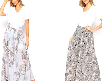 May include: Two women wearing white V-neck tops and long skirts. One skirt has a floral pattern with light blue, brown, and pink hues. The other skirt has a snakeskin pattern in shades of gray, brown, and beige. Both skirts are flowing.