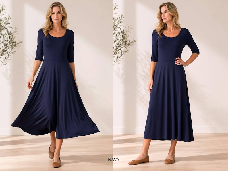 Op de afbeelding: Marineblauwe midi-jurk met een ronde hals en driekwartmouwen. De jurk heeft een getailleerd lijfje en een uitlopende rok. Het model draagt bruine ballerina's. Het woord "NAVY" staat onderaan de afbeelding.