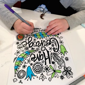 May include: A child colors a black and white drawing of a colorful design with the words "Come Home" in a whimsical font. The drawing includes flowers, leaves, and swirls. The child is using a purple marker to color the drawing.