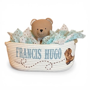 Peut inclure: Un panier en corde blanc avec le nom "FRANCIS HUGO" en lettres bleu clair. Un ours en peluche marron et du papier de soie bleu &agrave; pois marron sont &agrave; l'int&eacute;rieur. Une botte de cowboy marron est dessin&eacute;e sur le c&ocirc;t&eacute;.