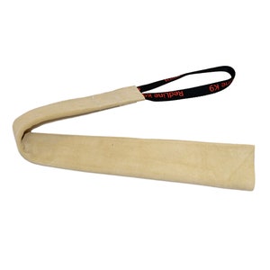 May include: A tan-colored dog training tug toy with a black handle. The handle has the text "RedLine K9" in red. The toy is made of a soft, durable material.