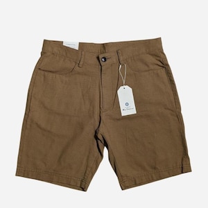 May include: Brown shorts with a button closure, front pockets, and a tag. The shorts are made of a textured fabric and have a classic design. The tag has a blue circle logo. These shorts are suitable for casual wear.